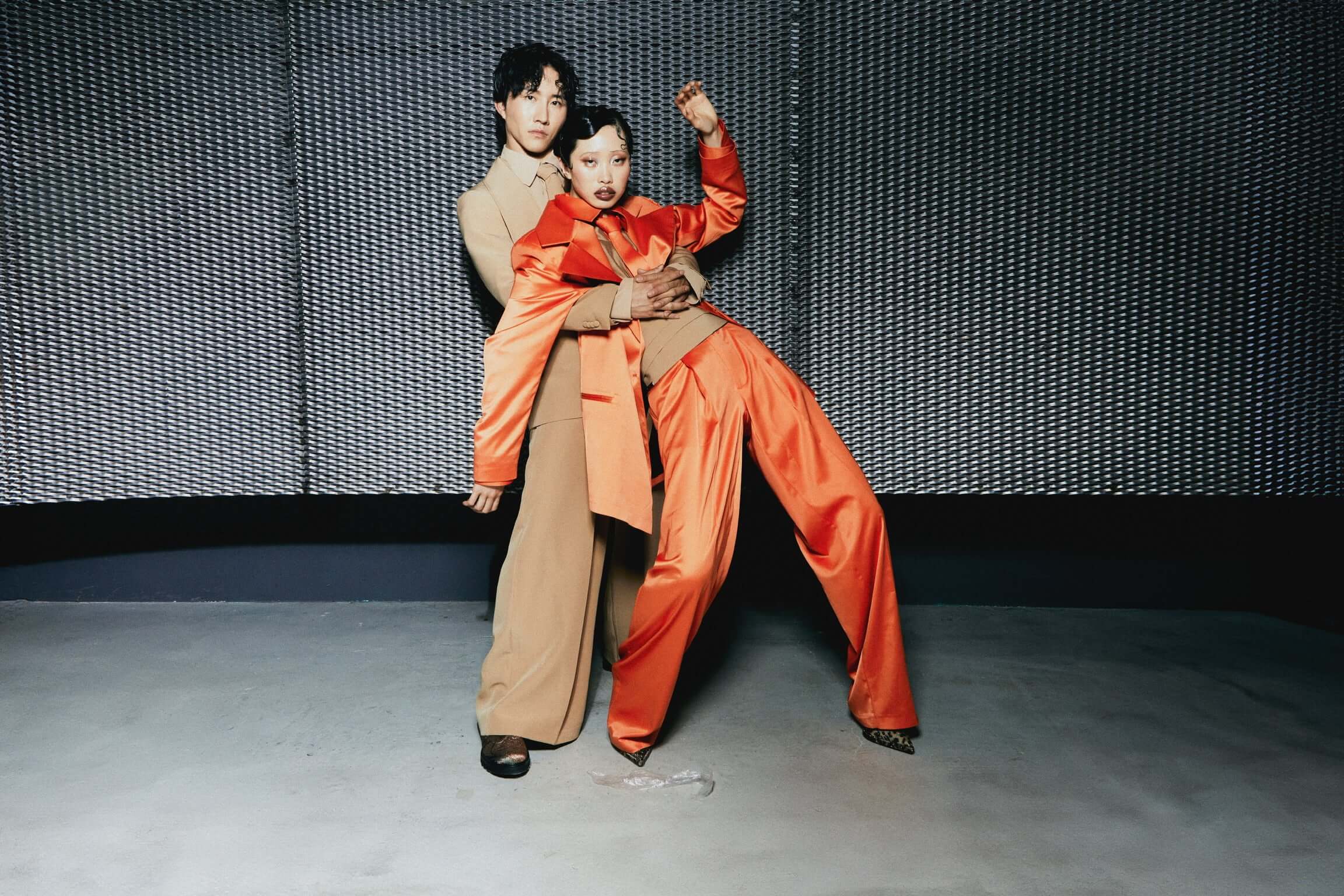 Pantalone Baggy Raso Arancione Modelli in abbigliamento contemporaneo, indossando pantaloni baggy raso arancioni e stile elegante in un ambiente urbano.